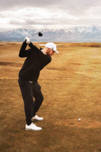 Golfer in mid-swing at the tee box.