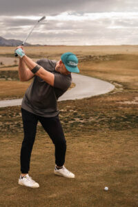 Golfer in mid-swing at the tee box.