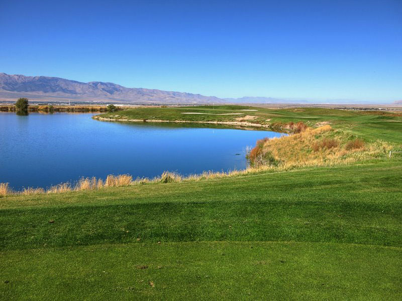 A lake borders the course, bending the fairway and green around it.